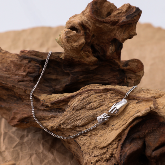 Предметне фото срібного браслета Лапка та ручка на фактурній корі дерева від ювелірного бренду Лучі LUCHI