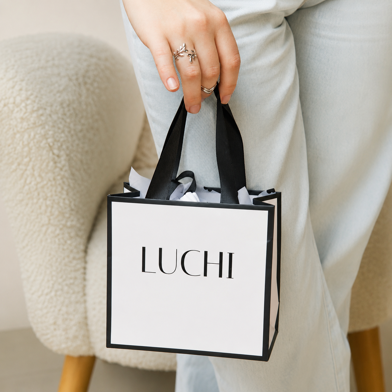 Дівчина тримає фірмовий пакет LUCHI та демонструє срібні прикраси